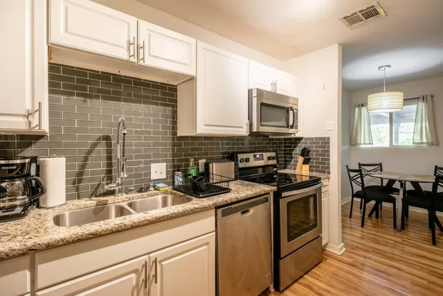 a kitchen with stainless steel appliances granite countertop a sink a stove counter space and cabinets