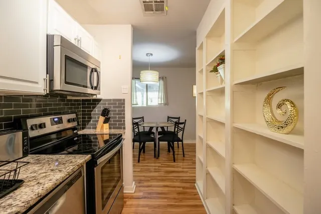 a kitchen with stainless steel appliances granite countertop a stove a sink and a microwave