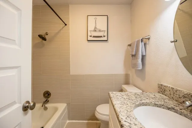 a bathroom with a granite countertop sink a toilet and a mirror