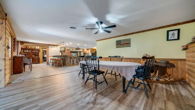 a kitchen with stainless steel appliances kitchen island granite countertop a table chairs in it and wooden floors