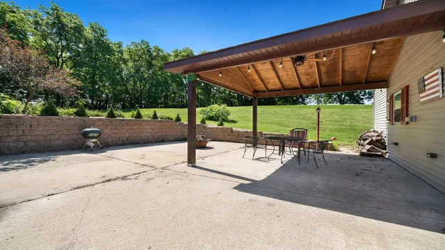 a view of a patio with a table and chairs under an umbrella with wooden fence