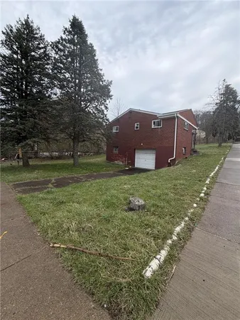 a view of a house with a big yard and large trees