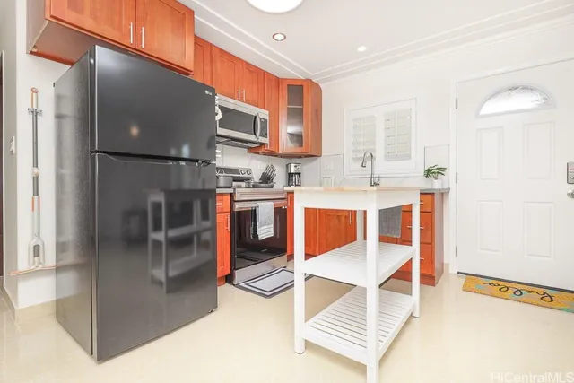 a room with stainless steel appliances kitchen island granite countertop a refrigerator and cabinets