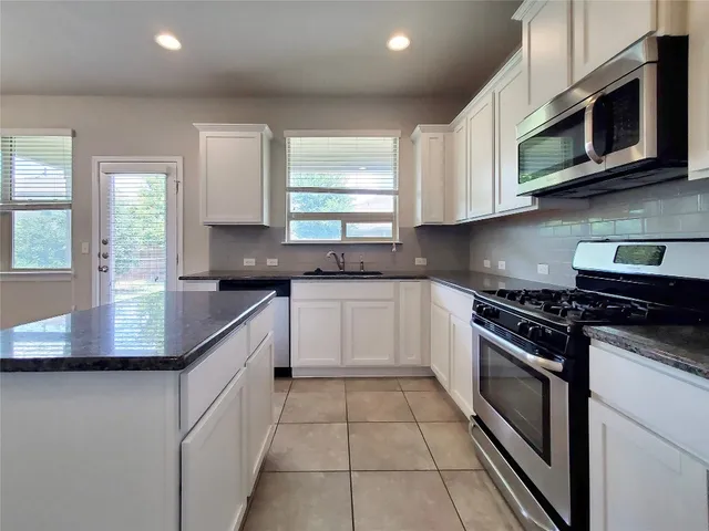 a kitchen with stainless steel appliances granite countertop a sink and a stove