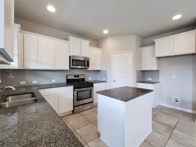 a kitchen with granite countertop a sink and a stove top oven