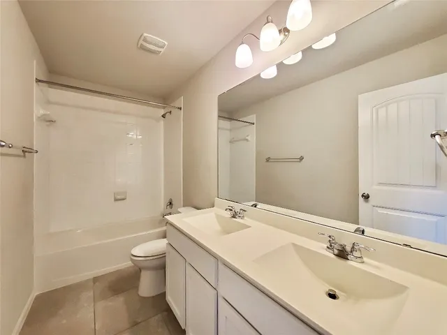a bathroom with a double vanity sink a toilet and shower