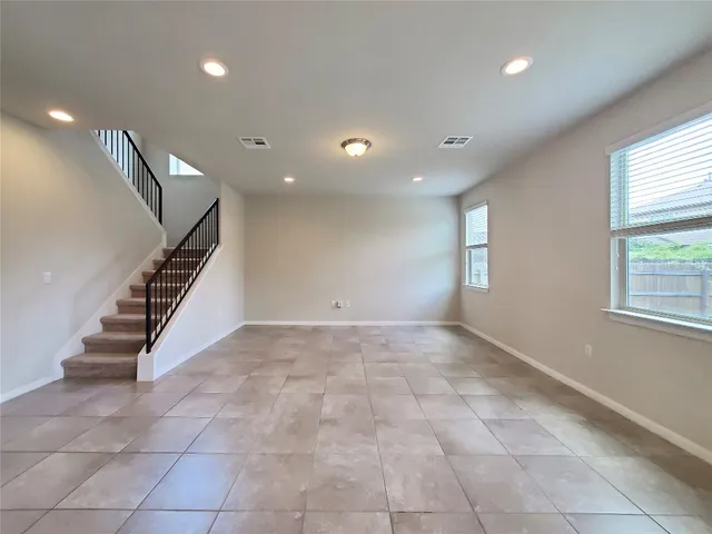 a view of an empty room with stairs and windows
