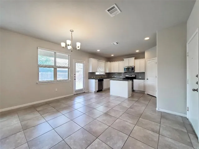a view of a kitchen with kitchen island granite countertop stainless steel appliances cabinets a sink and a window
