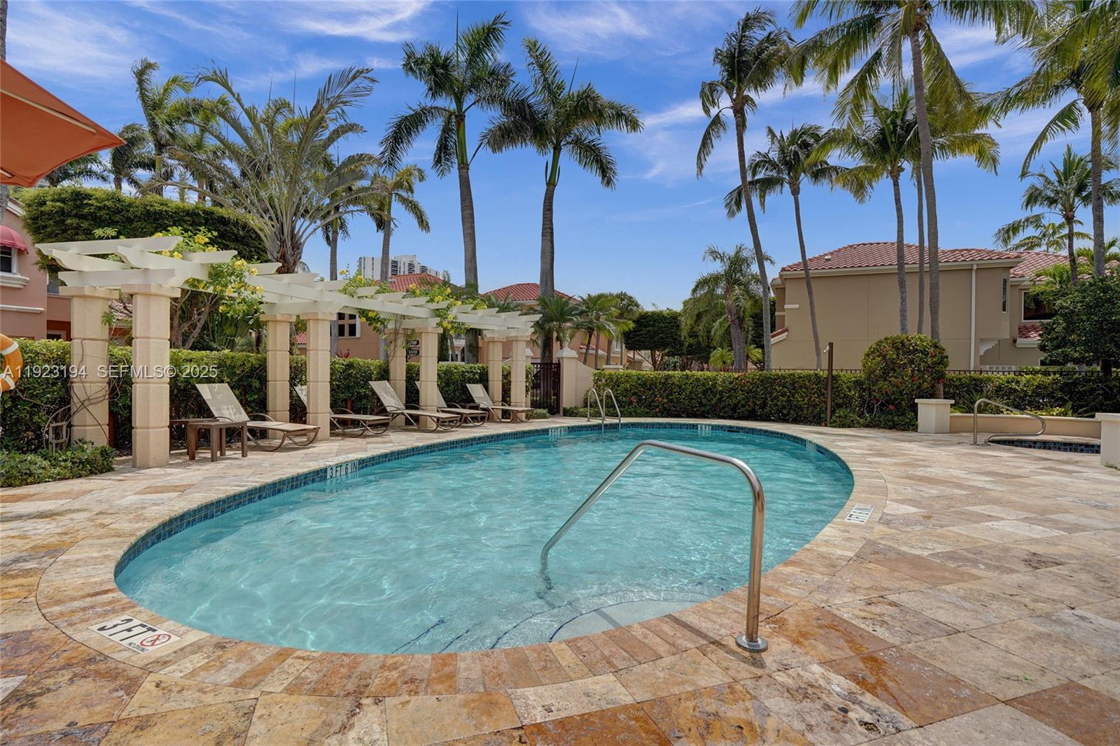 3757 Northeast 208th Terrace Aventura, FL 33180 - Photo 60 of 74 a view of a swimming pool with a lawn chair and palm trees