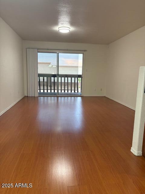 2121 West Royal Palm Road, Unit 2074 Phoenix, AZ 85021 - Photo 8 of 22 an empty room with wooden floor and windows