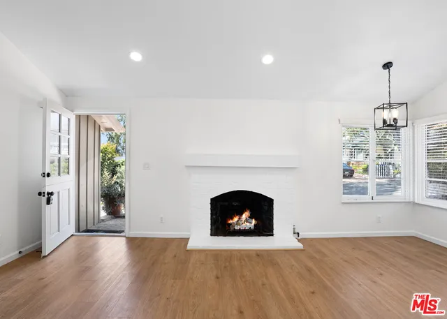 an empty room with wooden floor fireplace and windows