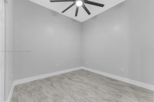 a view of empty room with wooden floor and ceiling fan
