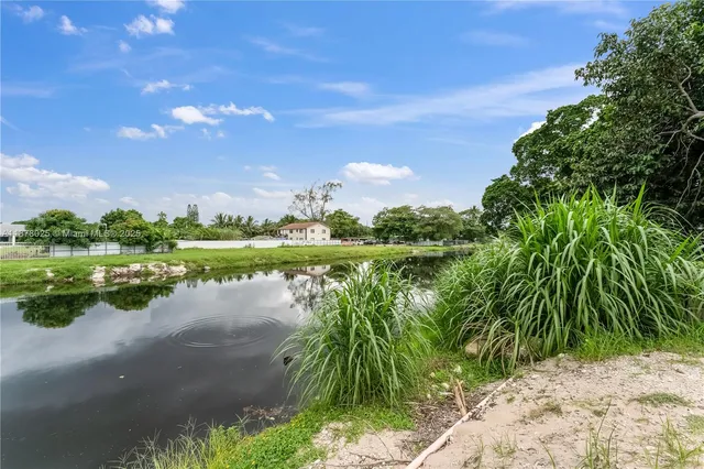 a view of a white house with a big yard and large trees
