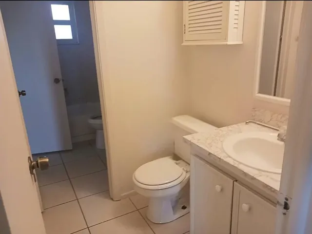 a bathroom with a granite countertop toilet and a sink
