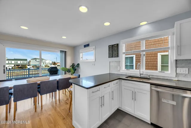 a kitchen with granite countertop white cabinets and white appliances with wooden floor