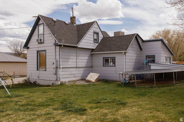 197 West 100 South Redmond, UT 84652 - Photo 7 of 41 Back of house featuring a chimney, a lawn, a trampoline, and a shingled roof