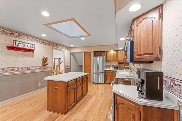 a large kitchen with kitchen island a large counter top space a sink stainless steel appliances and cabinets