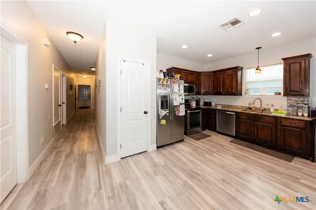 a kitchen with stainless steel appliances kitchen island granite countertop a refrigerator and a stove top oven