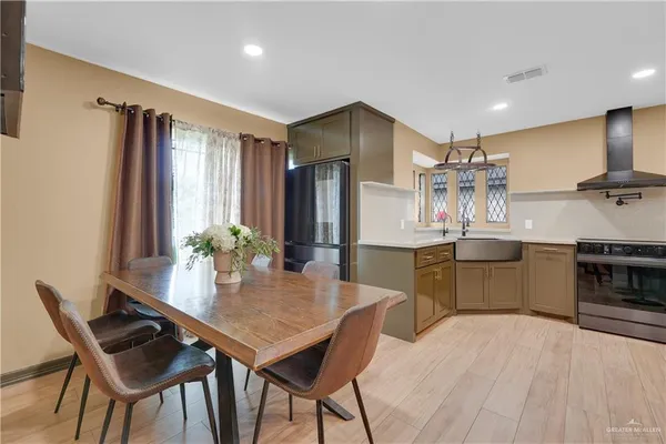 a kitchen with stainless steel appliances a dining table chairs stove and refrigerator
