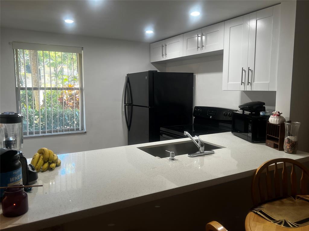 9091 Lime Bay Boulevard, Unit 114 Tamarac, FL 33321 - Photo 2 of 21 a kitchen with stainless steel appliances a refrigerator sink and cabinets