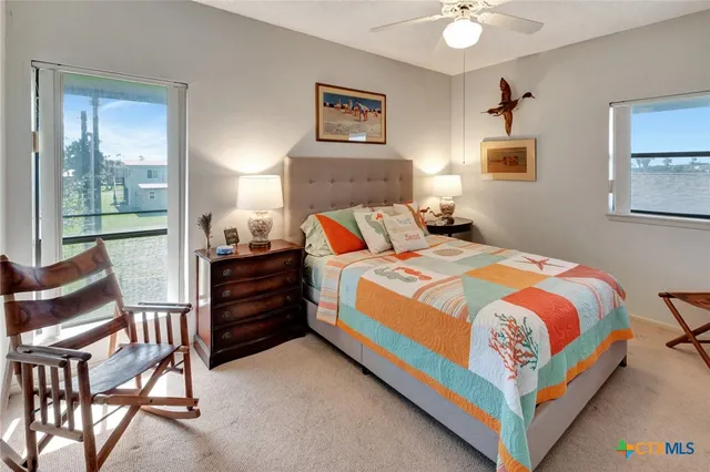 a bedroom with a bed chair and two windows