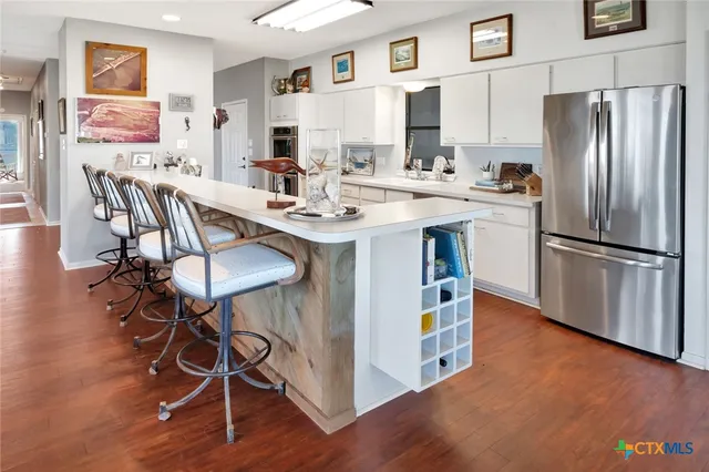 a kitchen with stainless steel appliances a dining table chairs refrigerator and sink