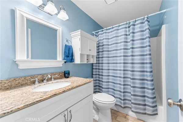 a bathroom with a granite countertop sink toilet and mirror