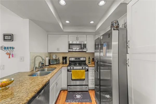 a kitchen with stainless steel appliances granite countertop a sink a refrigerator and a stove top oven
