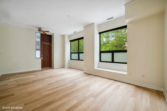 a view of an empty room with a window and wooden floor