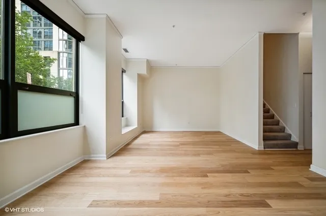 a view of an empty room with wooden floor and windows