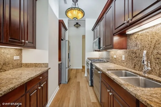 a kitchen with granite countertop a sink a stove oven and cabinets