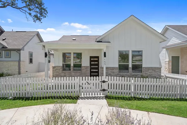 a front view of a house with a small yard and wooden fence