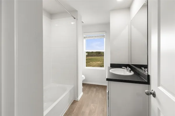 a bathroom with a granite countertop sink and a bathtub