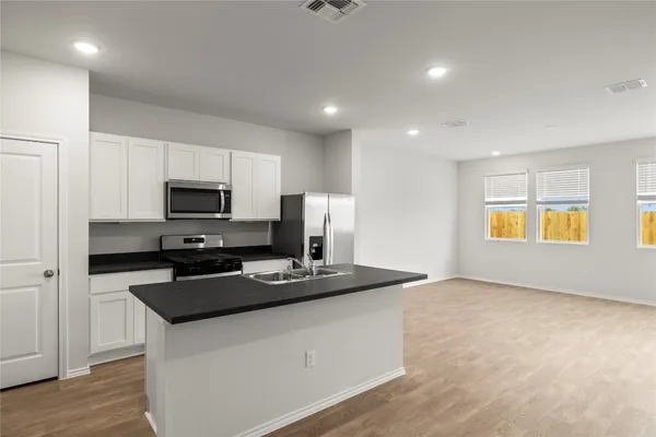 a kitchen with stainless steel appliances a stove a sink a refrigerator a microwave a sink and cabinets