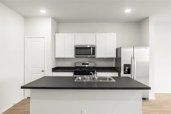 a kitchen with stainless steel appliances granite countertop a sink a microwave and refrigerator