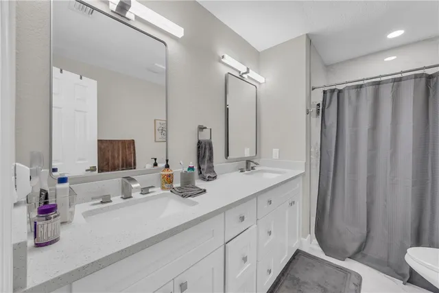 a bathroom with double vanity sink a mirror and shower