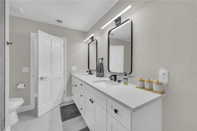 a bathroom with a double vanity sink mirror and toilet
