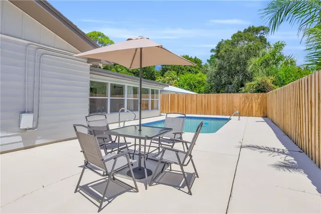 a patio with a table and chairs under an umbrella