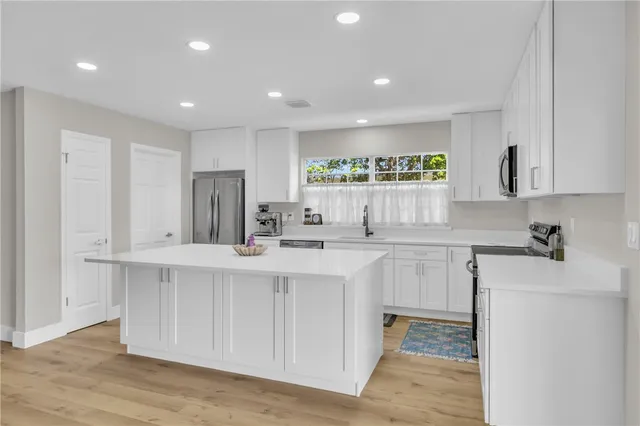 a kitchen with white cabinets and sink
