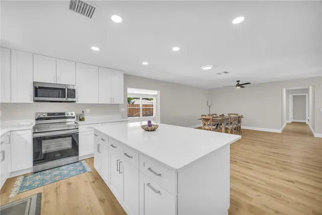 a large white kitchen with wooden floor