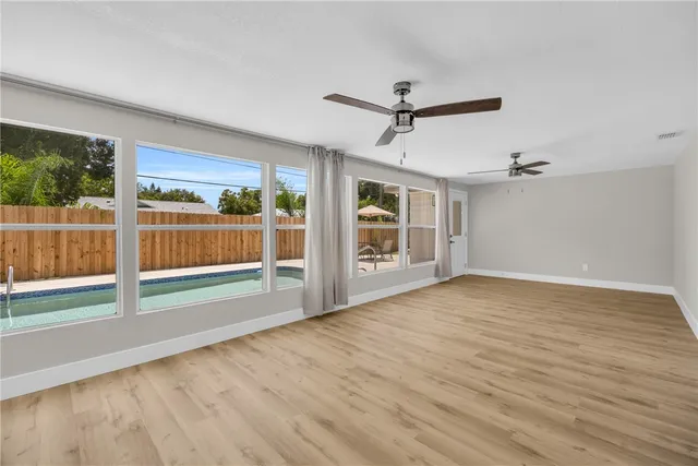 a view of empty room with wooden floor and fan