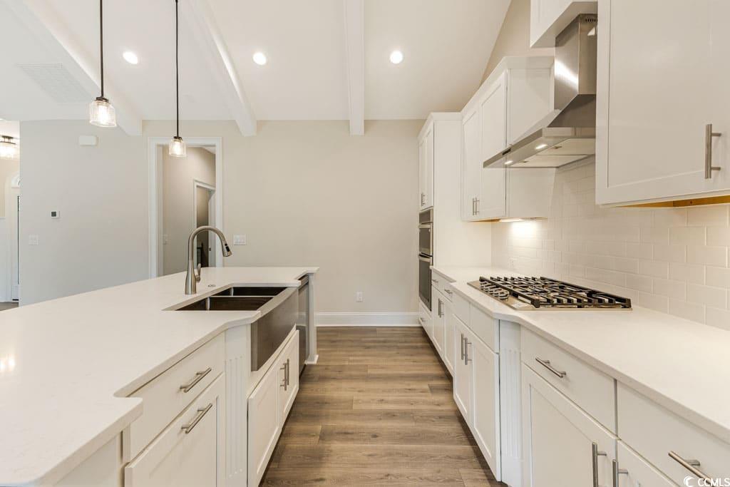 394 Sea Trail Drive West Sunset Beach, NC 28468 - Photo 12 of 40 Kitchen featuring white cabinets, wall chimney range hood, recessed lighting, backsplash, and light wood-style floors