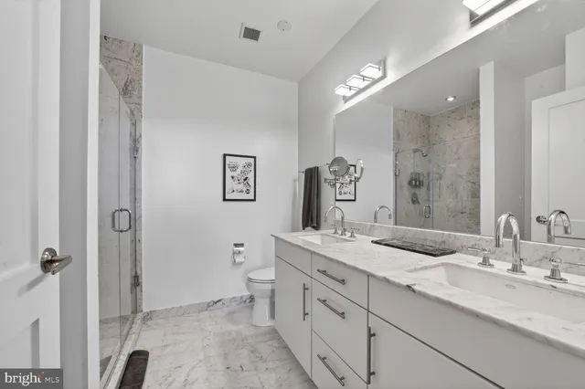 a bathroom with a sink double vanity granite and a toilet