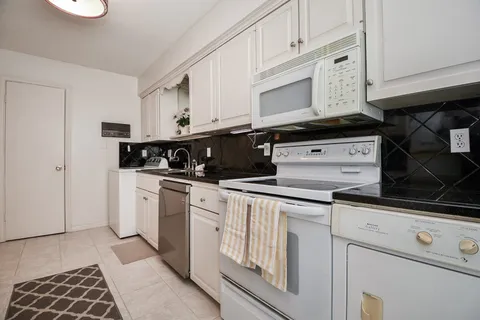 a kitchen with white cabinets and appliances
