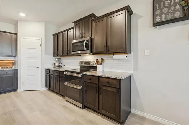 a kitchen with stainless steel appliances granite countertop a refrigerator and a stove top oven