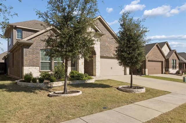 a front view of a house with garden and trees