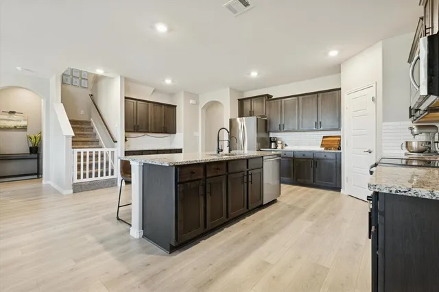 a kitchen with stainless steel appliances a sink a stove a microwave a refrigerator and cabinets