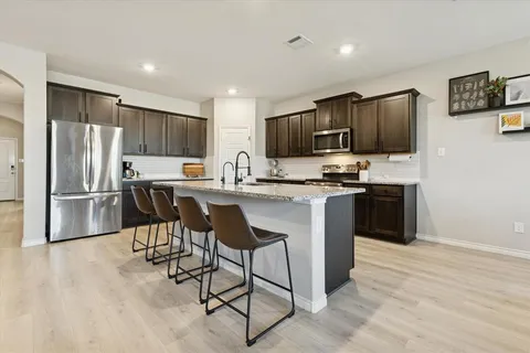 a kitchen with kitchen island granite countertop stainless steel appliances a stove a sink a refrigerator cabinets and a center island