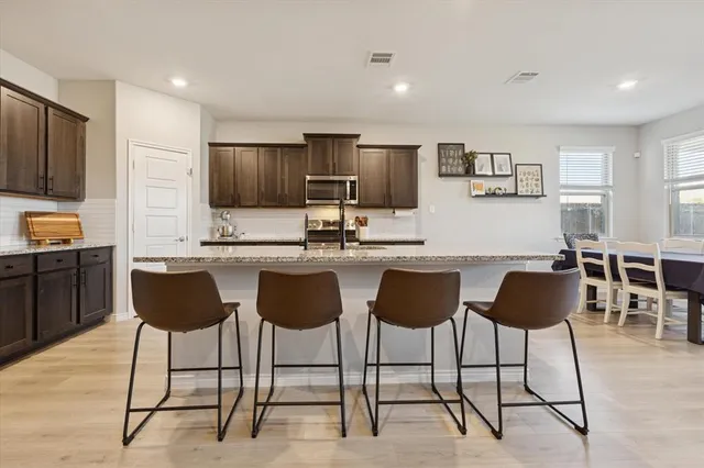 a kitchen with granite countertop a refrigerator and chairs