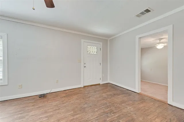 an empty room with wooden floor and kitchen view